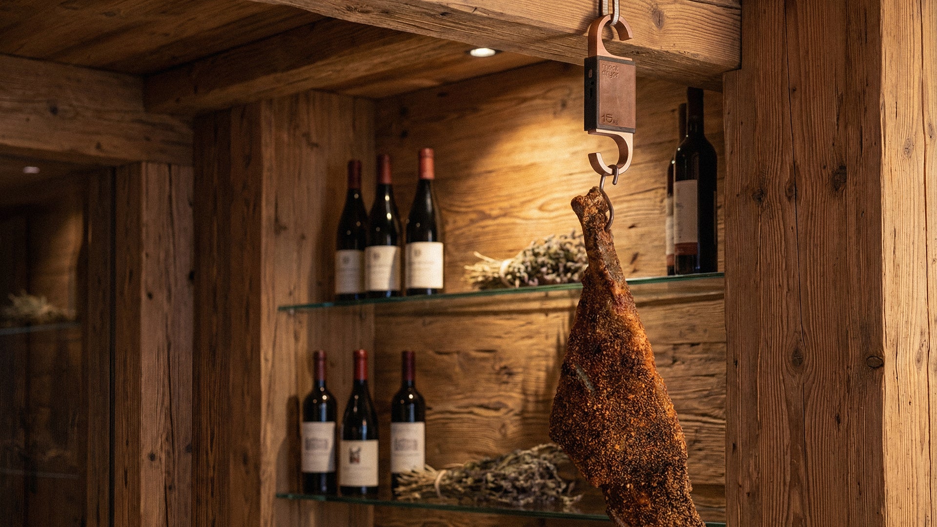 Wine bottles on shelves in a rustic wooden room with cured meats, prosciutto, serrano