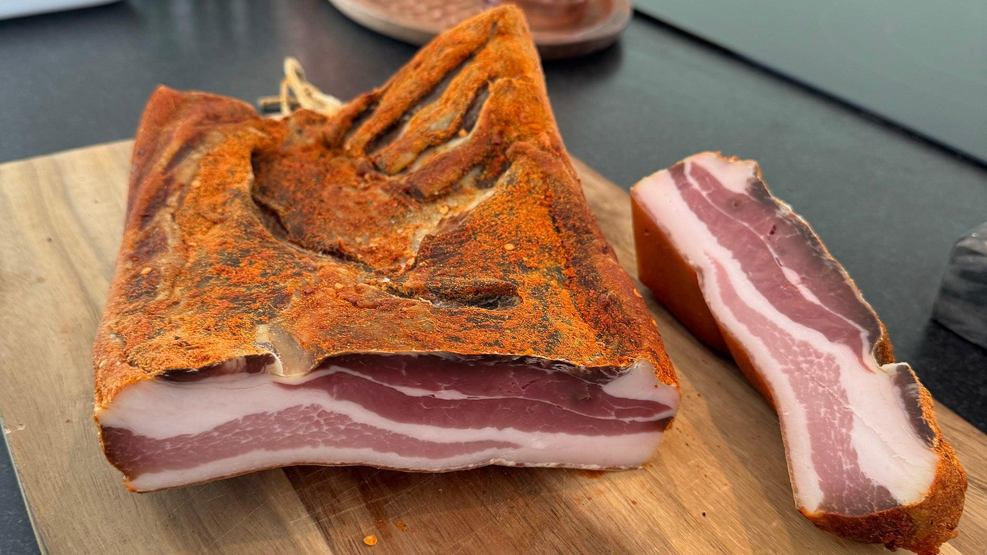 Dried Pancetta meat on a wooden cutting board with a blurred background